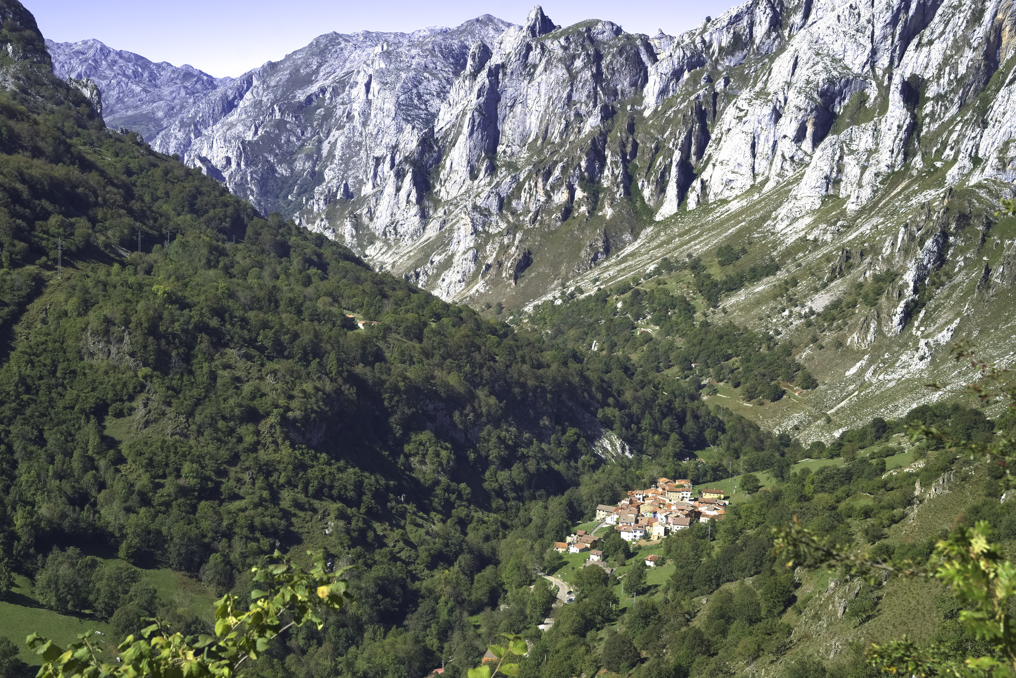 Looking down a forested and rocky valley towards the village of Tielve which lies at the bottom right of the image