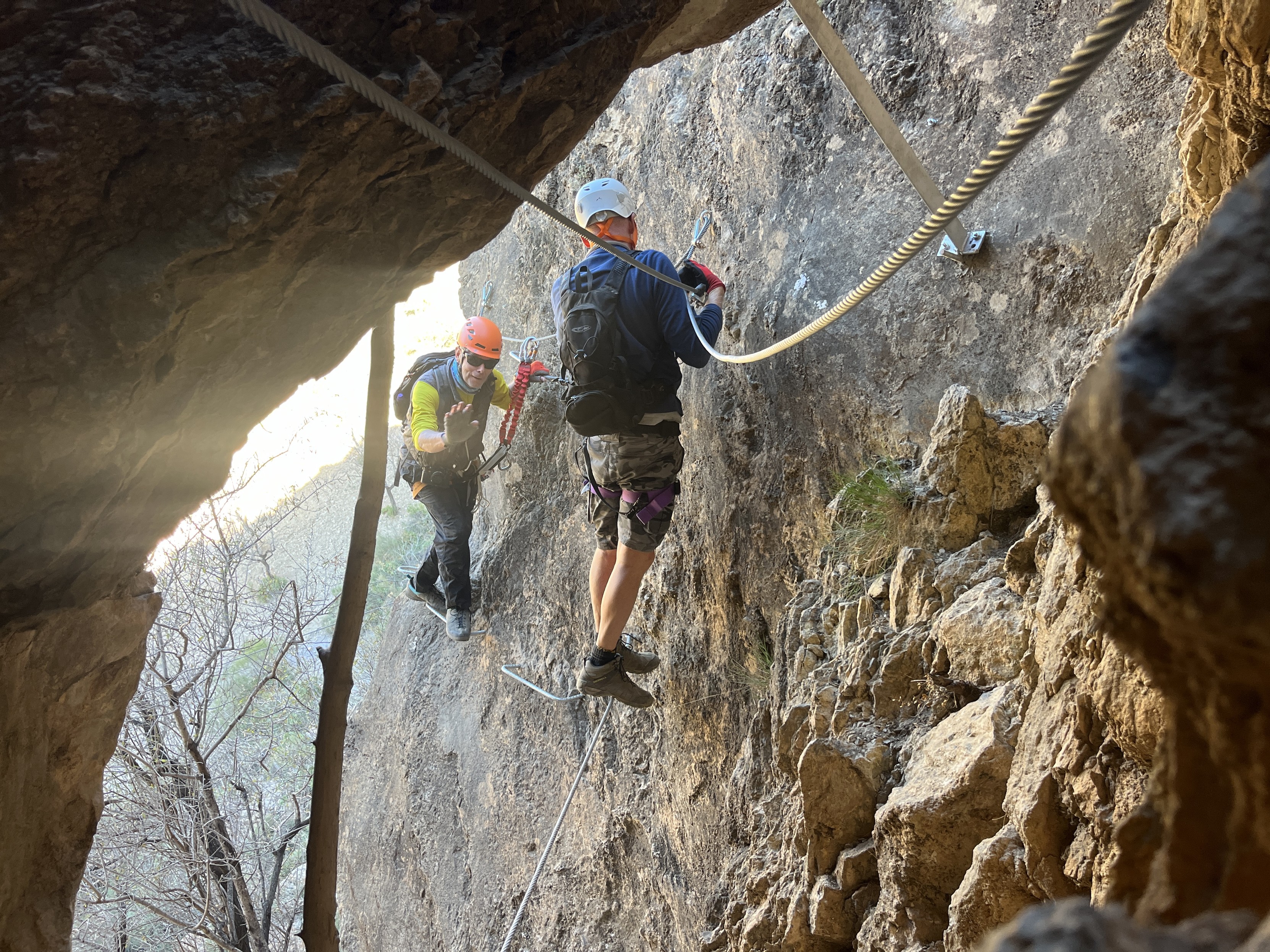 2 people practice via ferratas in Andalucia. Steep ladders, cables and zip lines. Here entering a cave