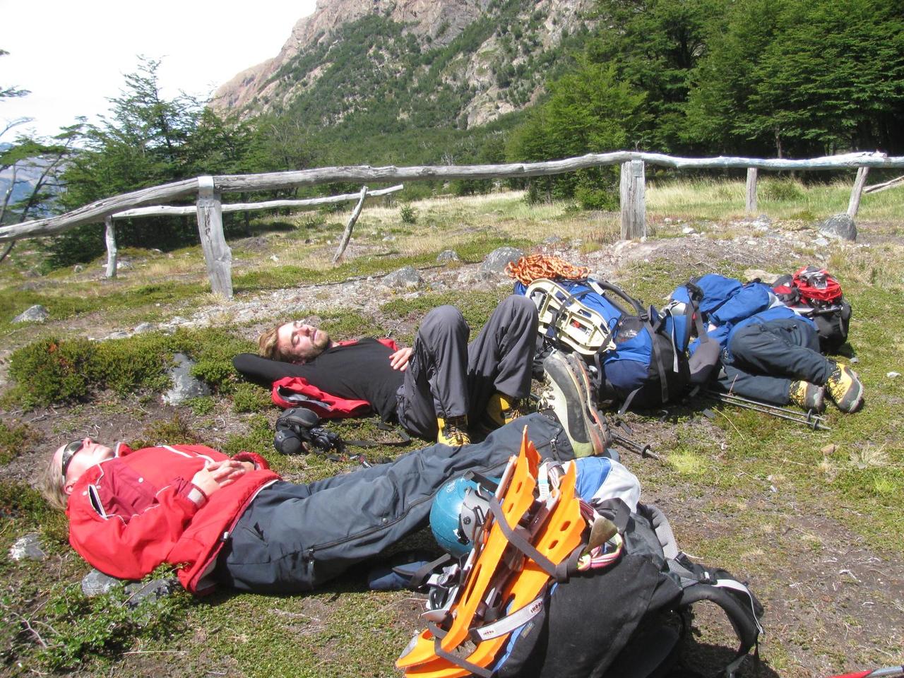 4 utterly wasted people crash out in full mountain gear on a grassy bank to sleep