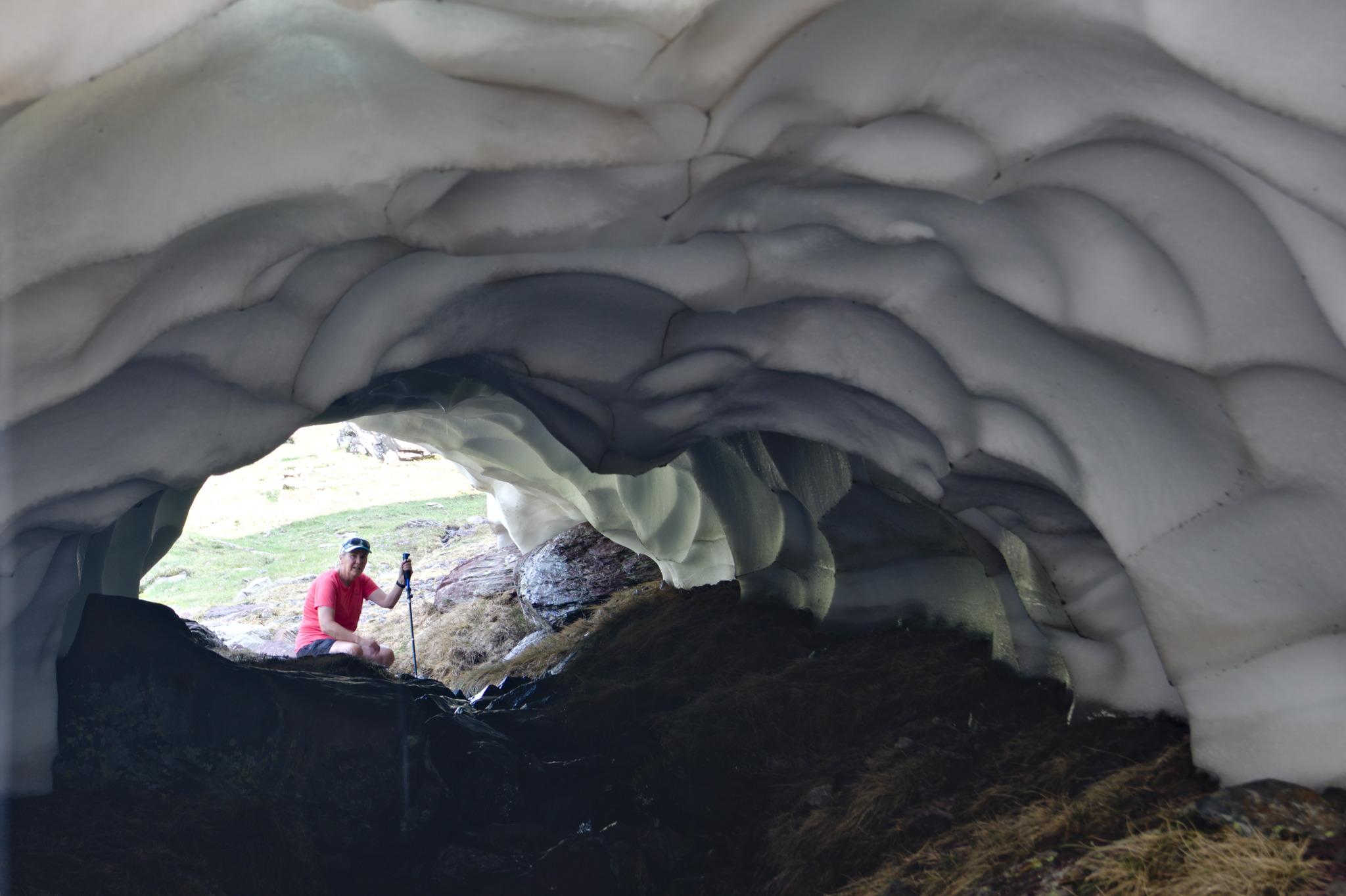A person is seen at the far side of a small stream surrounded by snow