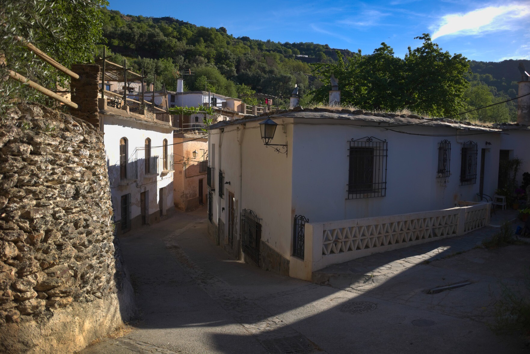 An early morning village scene in the village of Ferreirola in the Alpujarra. Some of the street is in shadow whilst the first rays of the sun illuminate the rest of the buildings