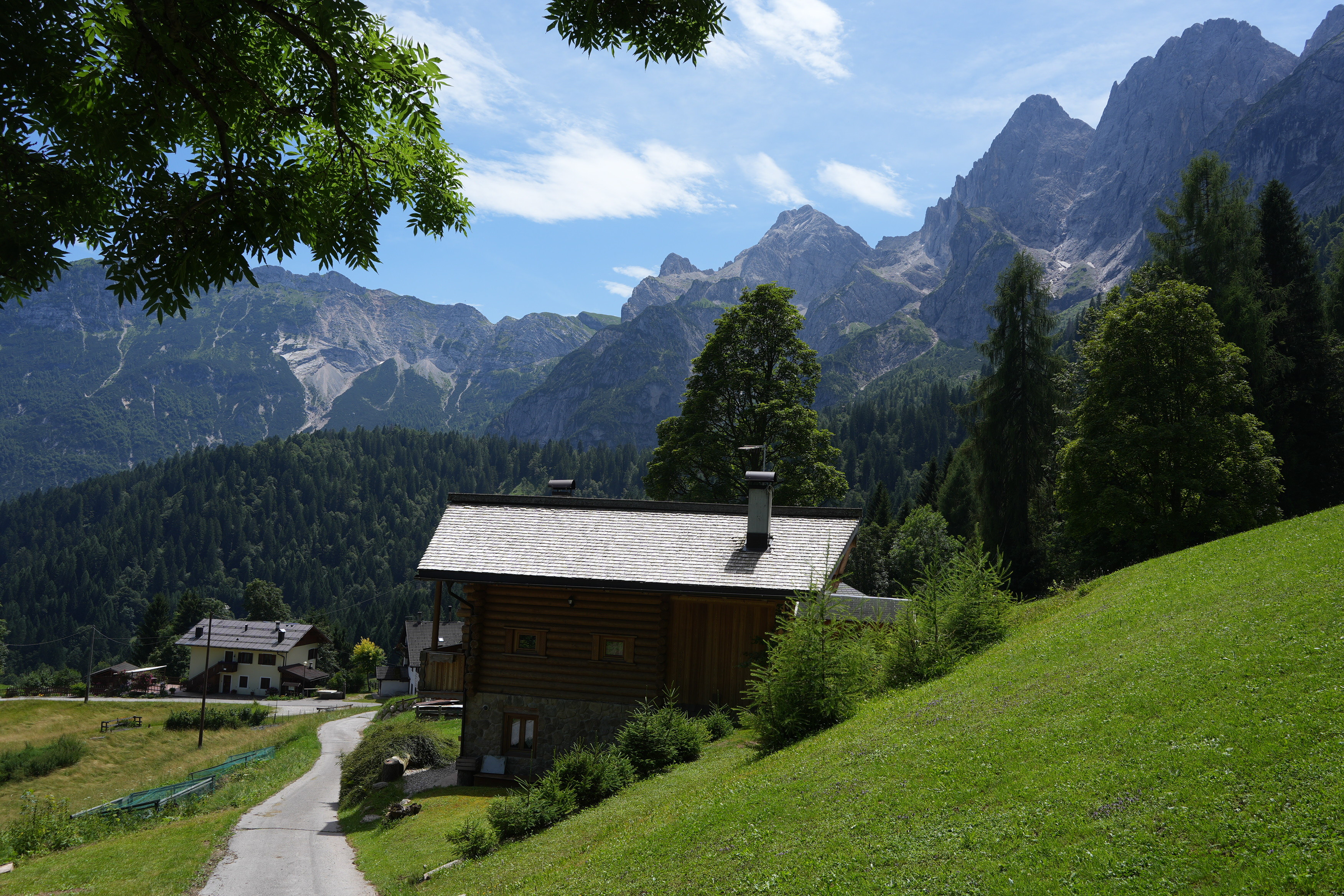 Small buildings sit in grassy meadows with huge peaks towering above