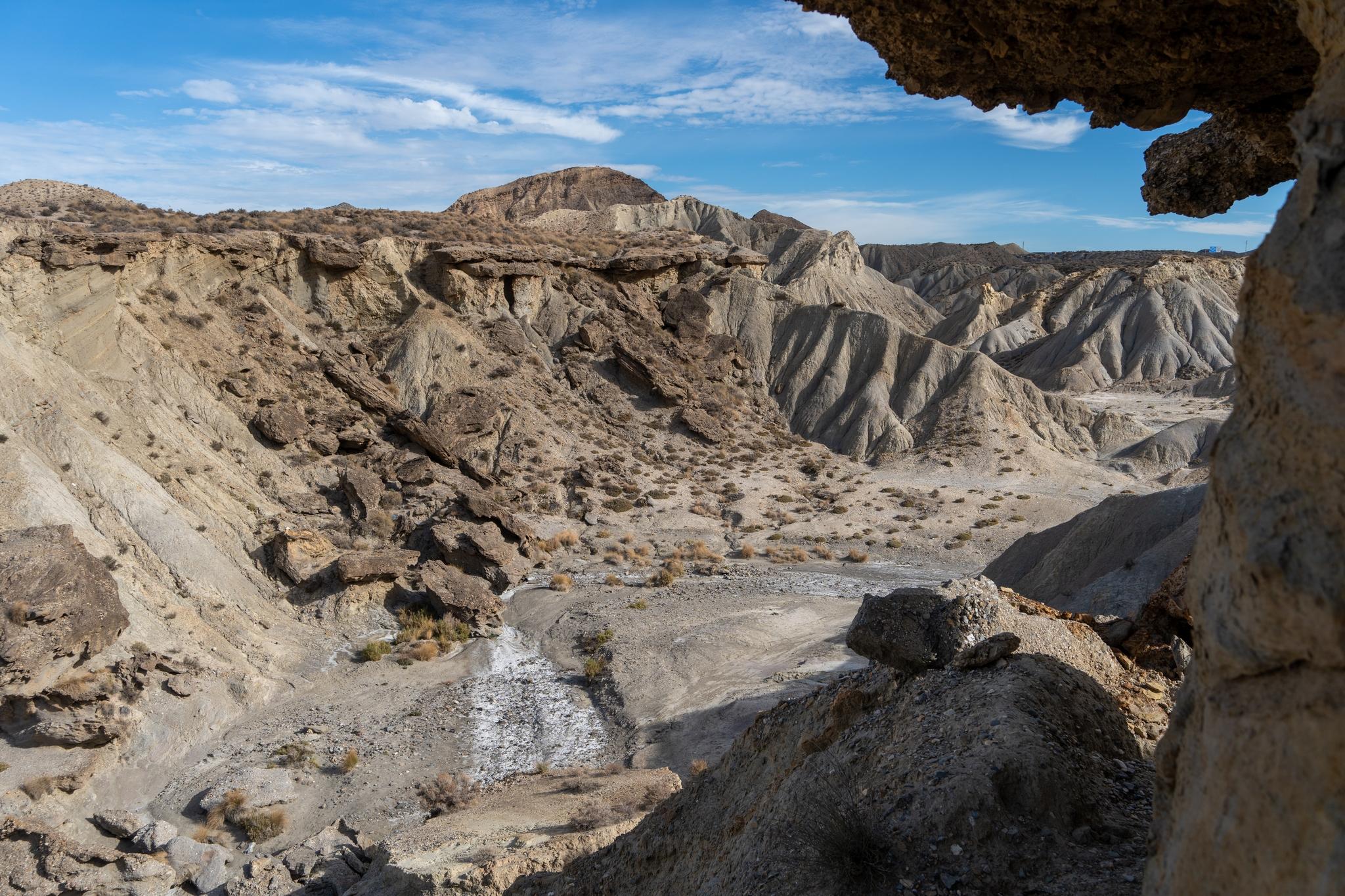 A view down over a chaotic desert badlands landscape with ravines, landfalls and arid valleys.