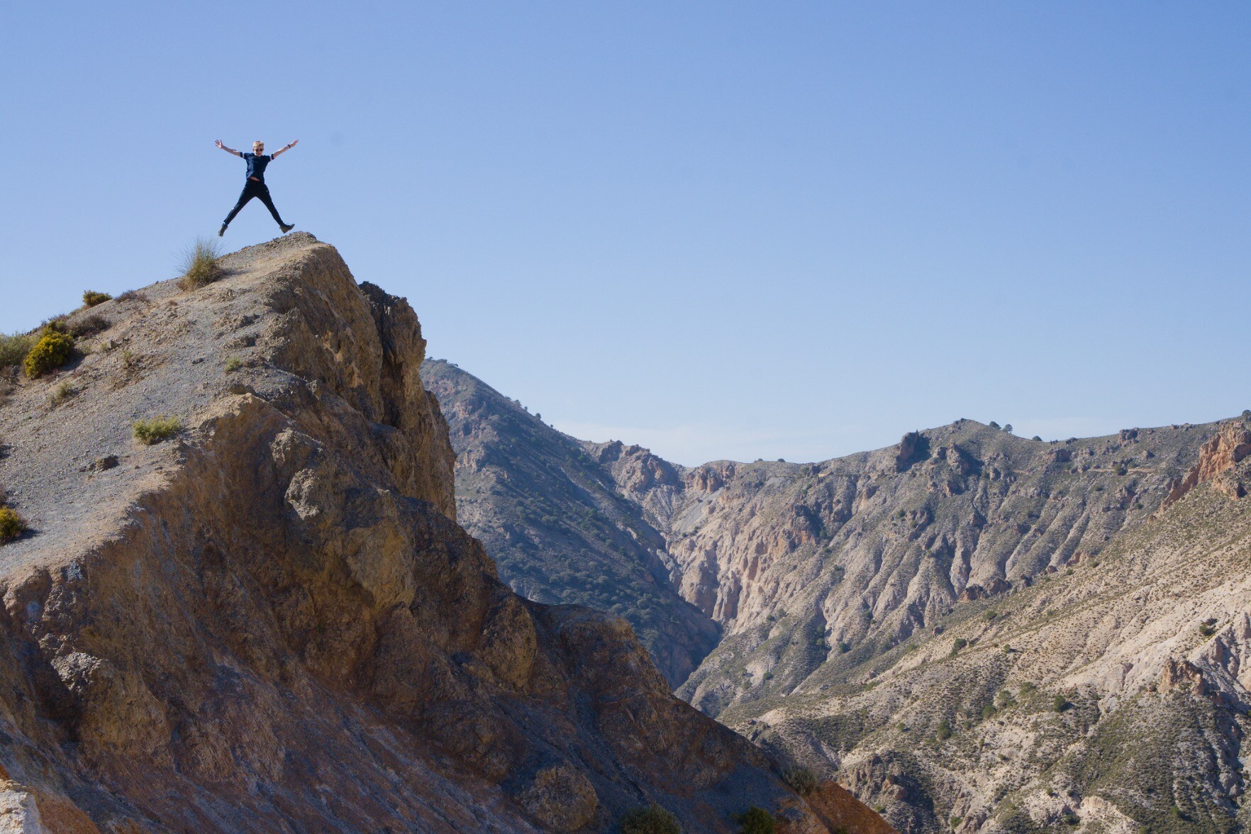 Man star jumping on the top of a mountain