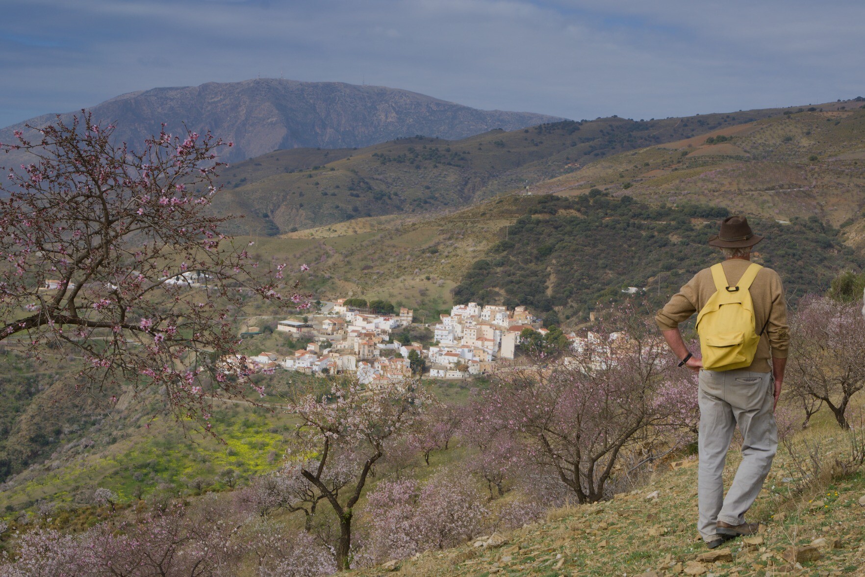 Man stood looking across to white village of Polopos in the Sierra de Contraviesa, Spain. Mountain of Sierra de Lujar behind