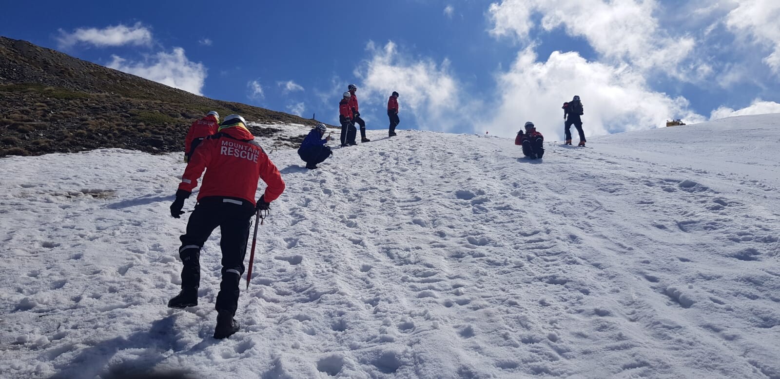 Training for Mountain Rescue Teams. People walking up and sliding down a snow slope