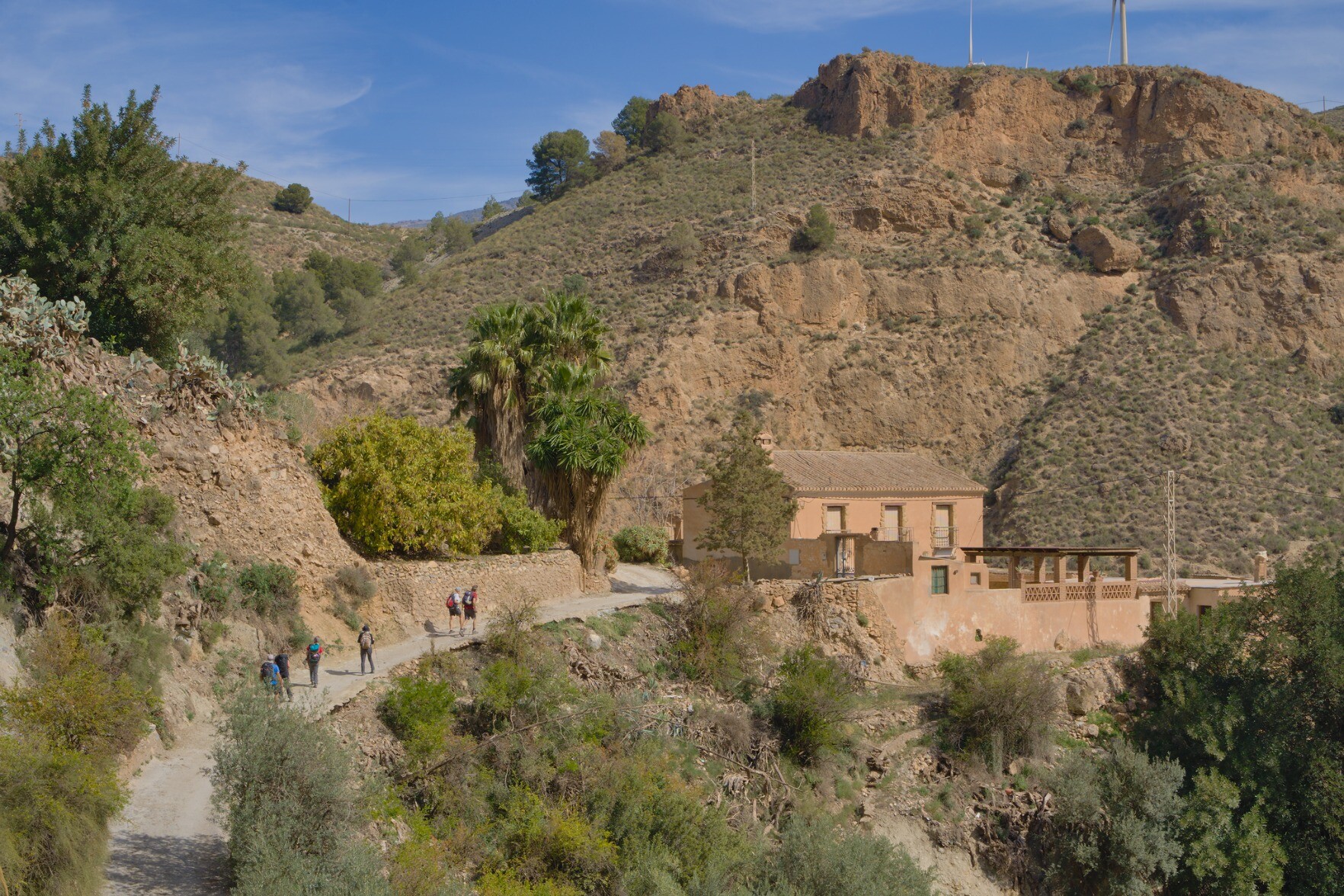 People hiking along 
a track to a house, Spain