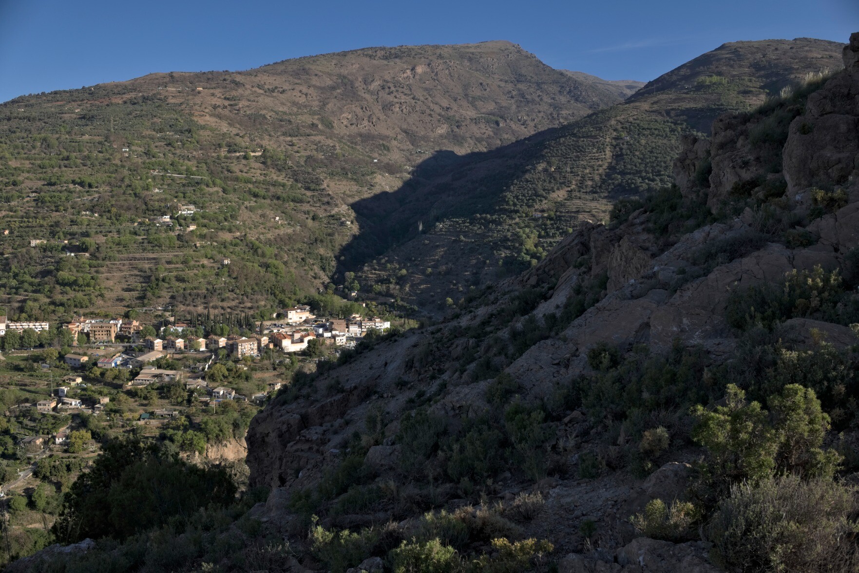 The outskirts of the town of Lanjaron with the deep valley of the Rio Lanjaron in shade running up to the right.