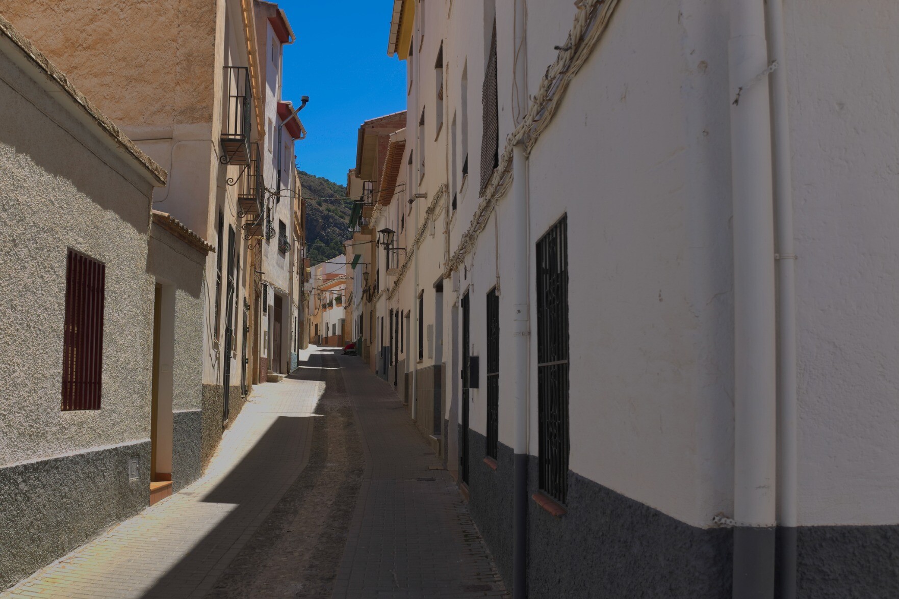 A street scene in Niguelas, Andalucia. The street is deserted, the right hand side of the street is in shadow