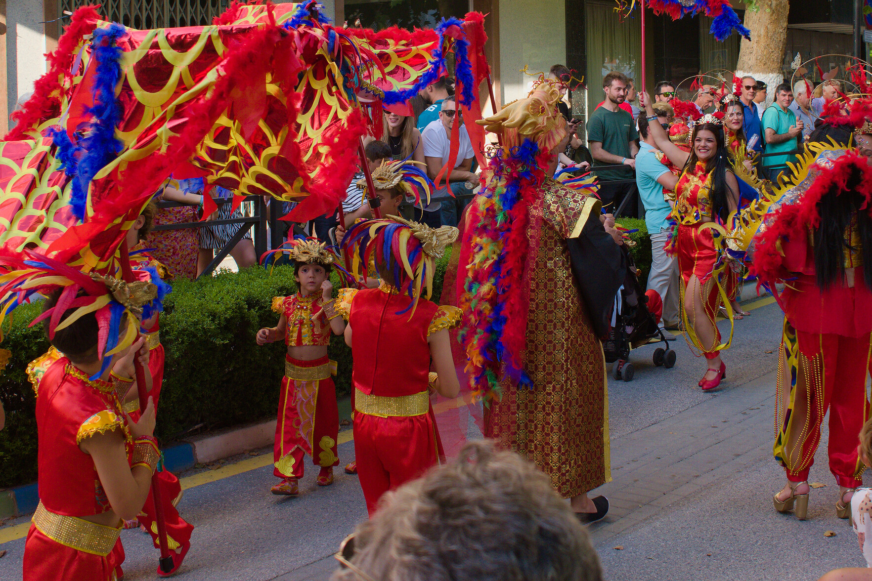 A group of people dressed in red and yellow attire dance through the streets