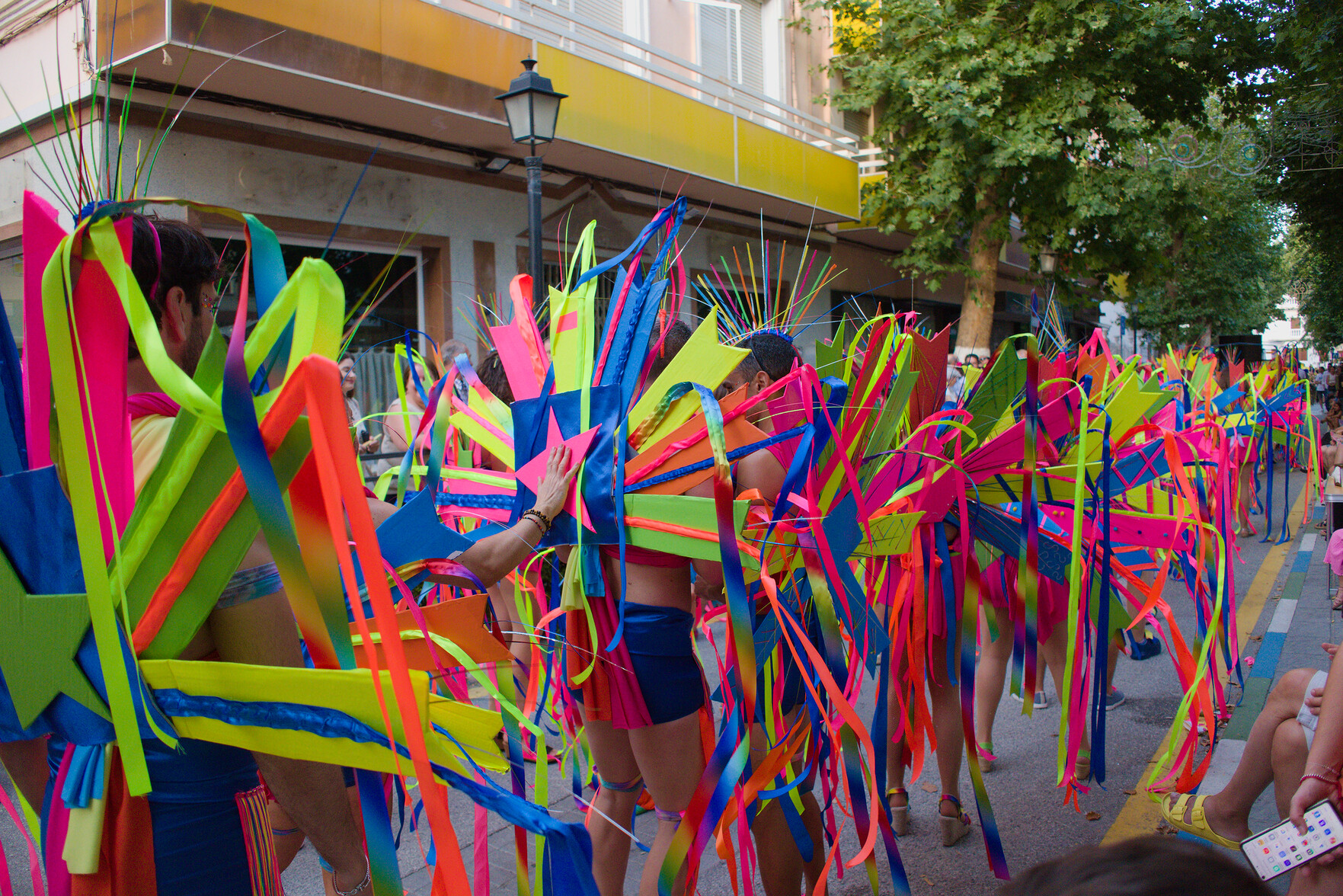 people dressed in multi colored outfits dance their way through streets of a spanish town