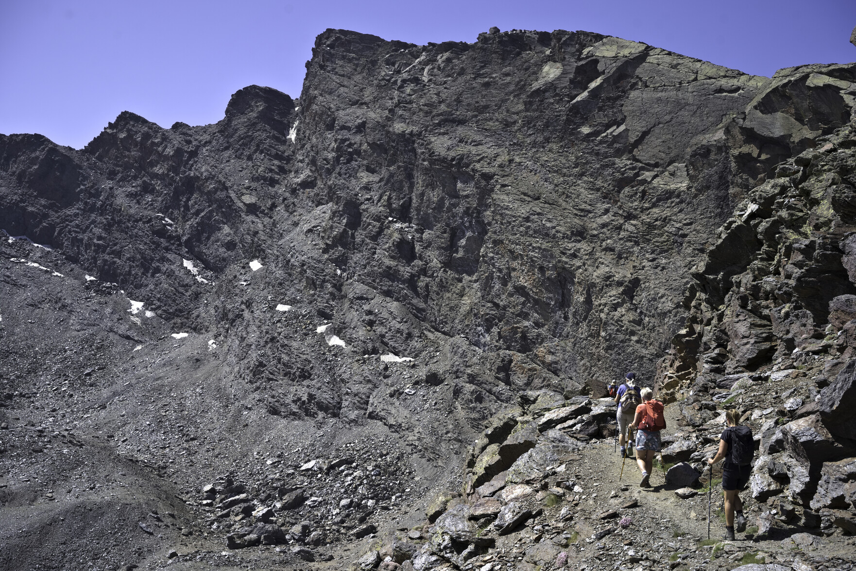 The north face of the peak of Veleta and to the bottom right some hikers approach along a narrow path