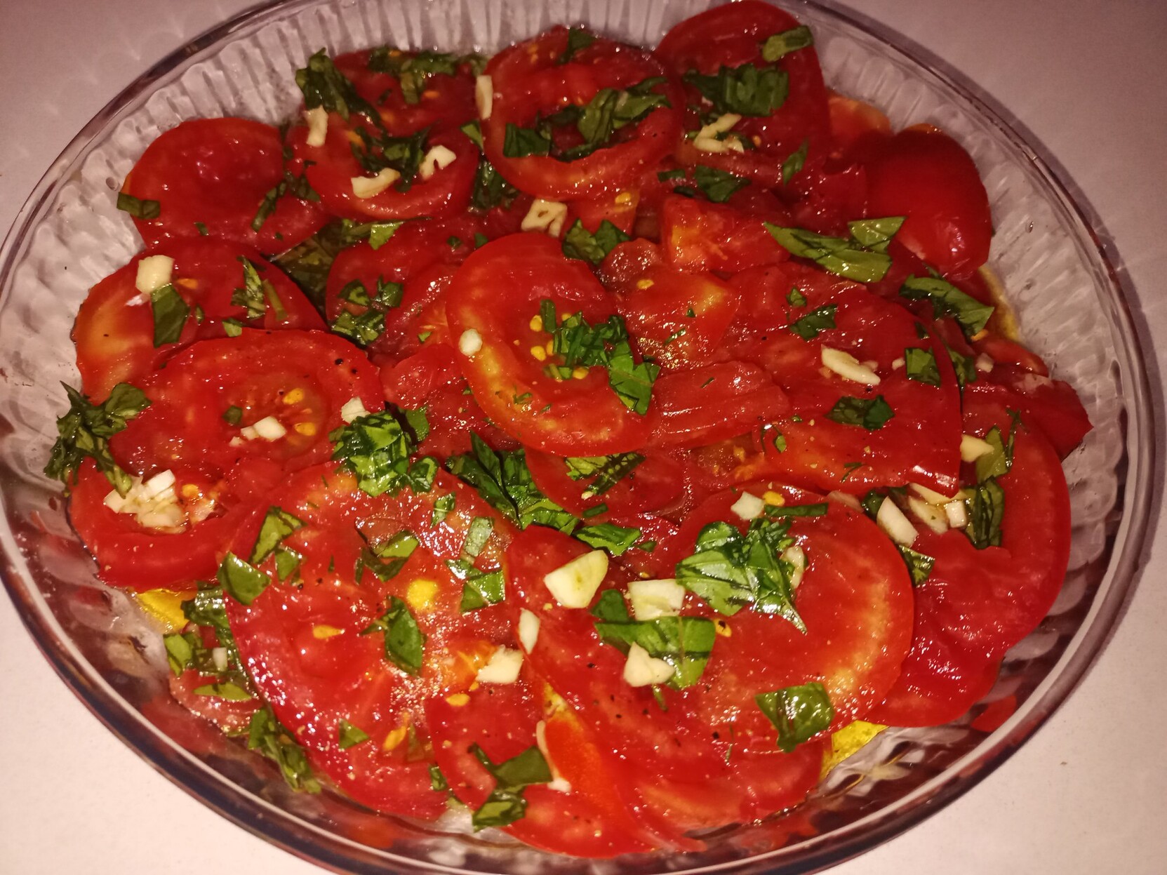 A plate of bright red tomatoes and chopped green basil leaves