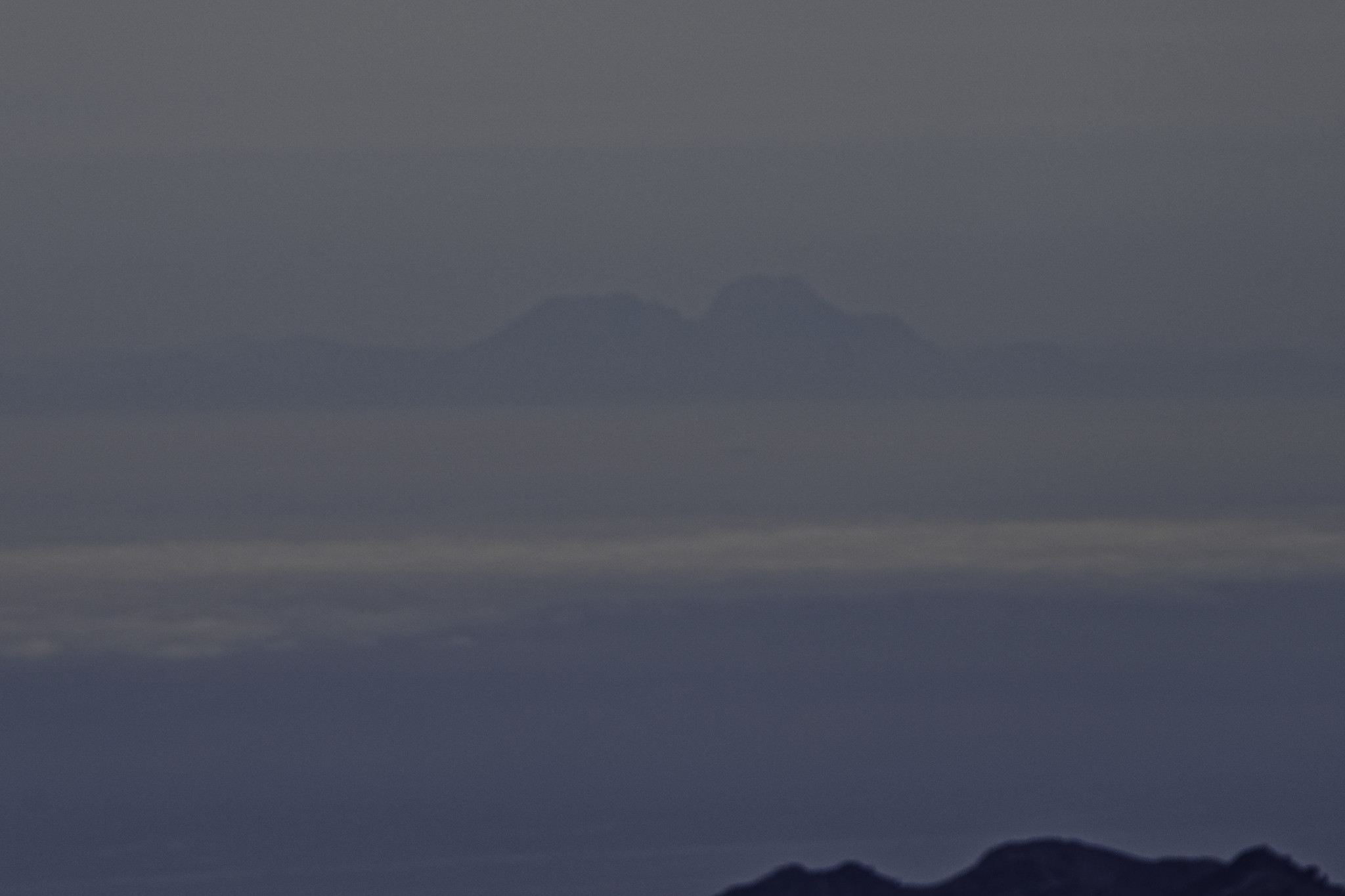 Layers of sea and cloud over the Mediterranean Sea. At the back rises a shadowy outline of some mountains