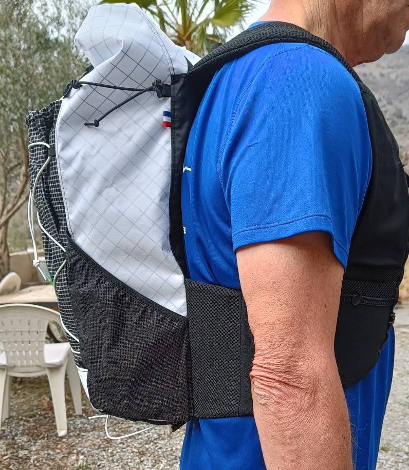 A black and white backpack sits on the back of a person with a blue t-shirt