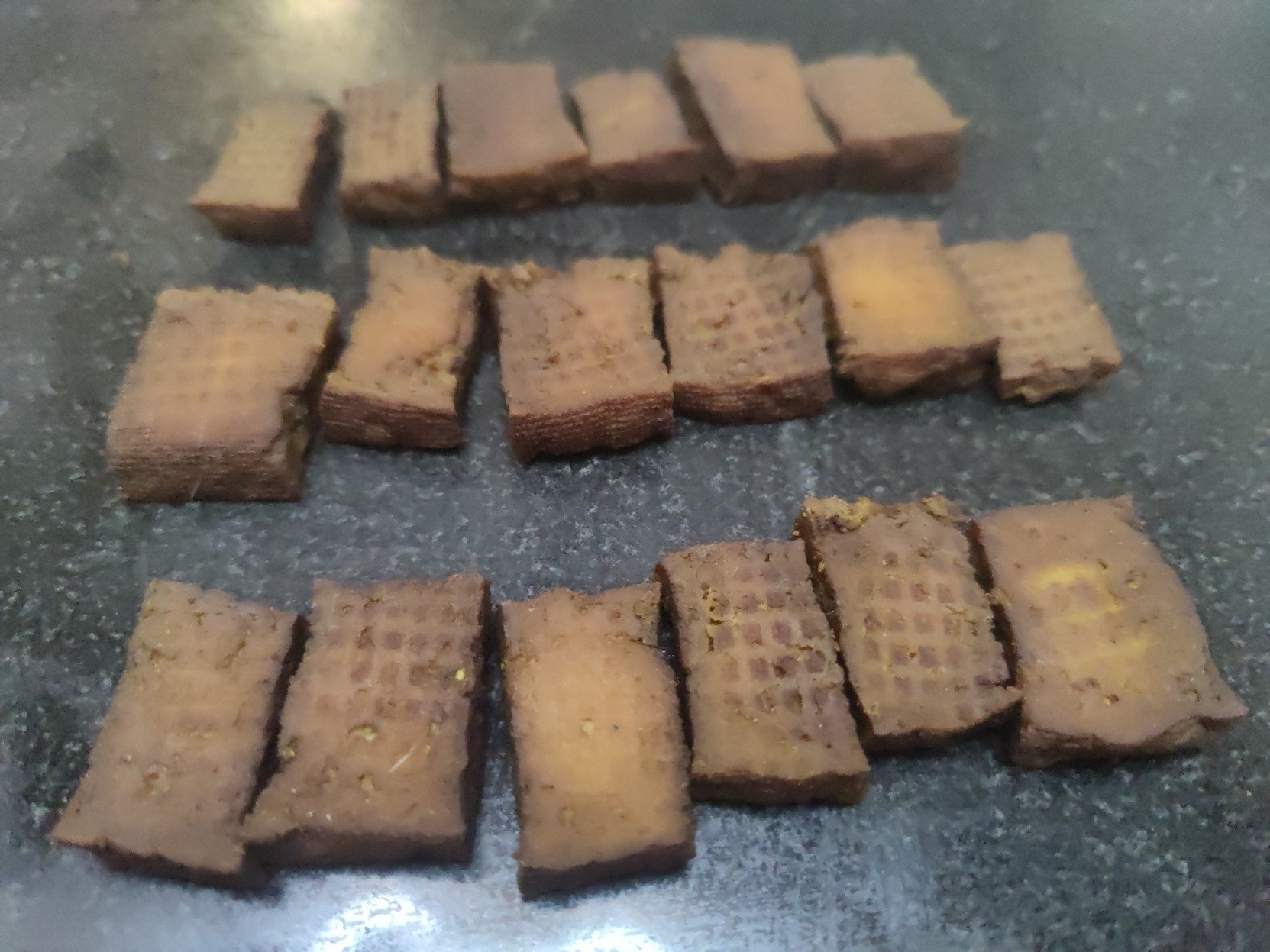 Rows of brown dehydrated and marinated tofu awaiting vacuum sealing.