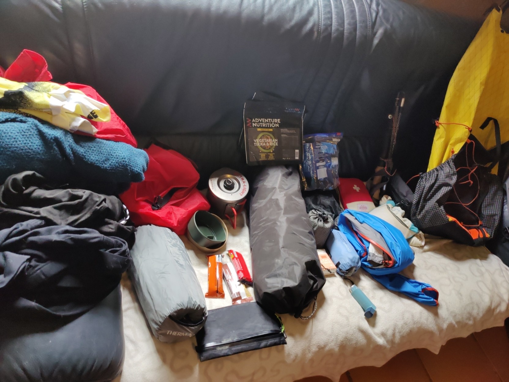 A colourful selection of mountain outdoor gear sits displayed on  a black sofa