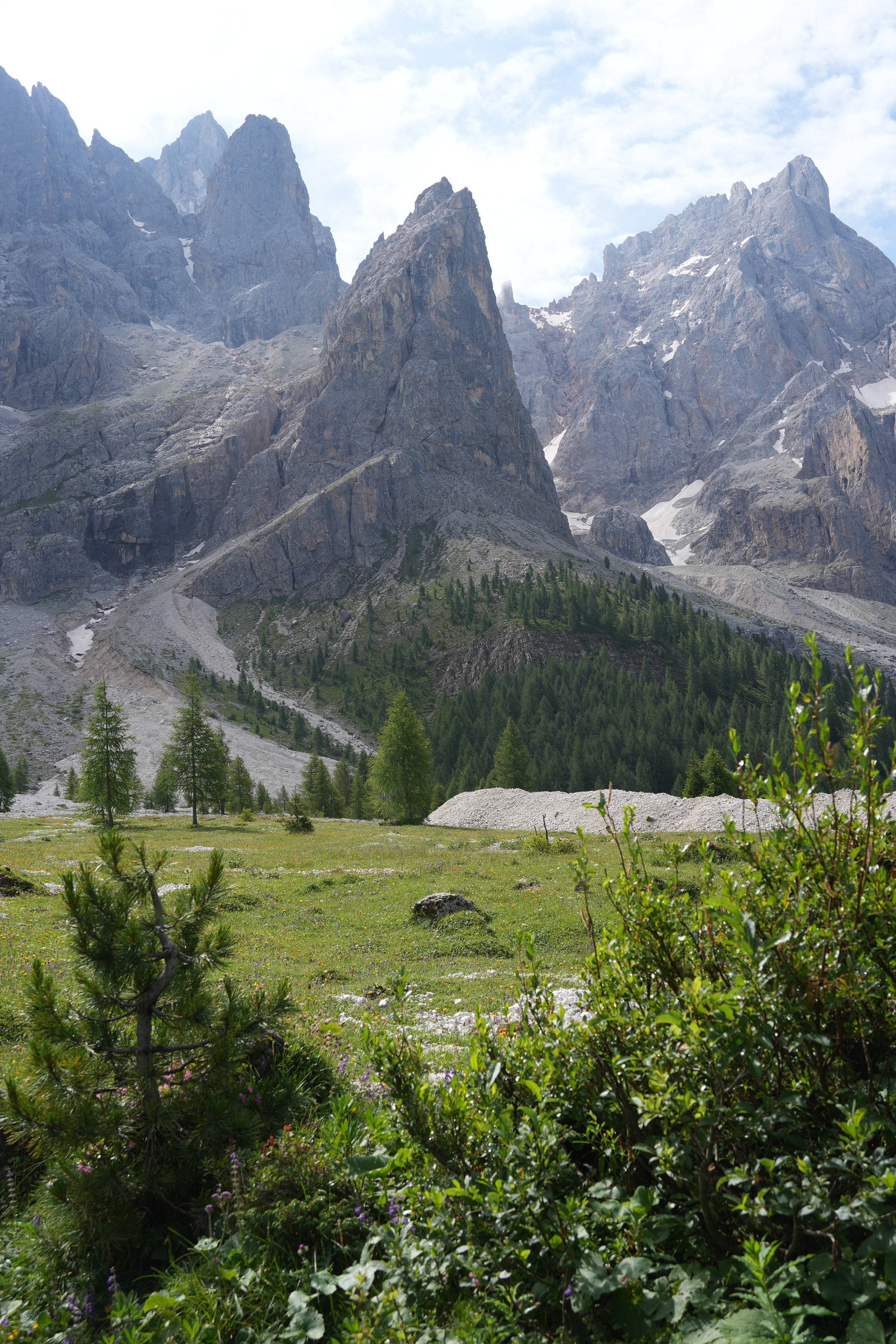 An upper area of barren rock faces and verticality contrasts with the green lushness of a valley floor