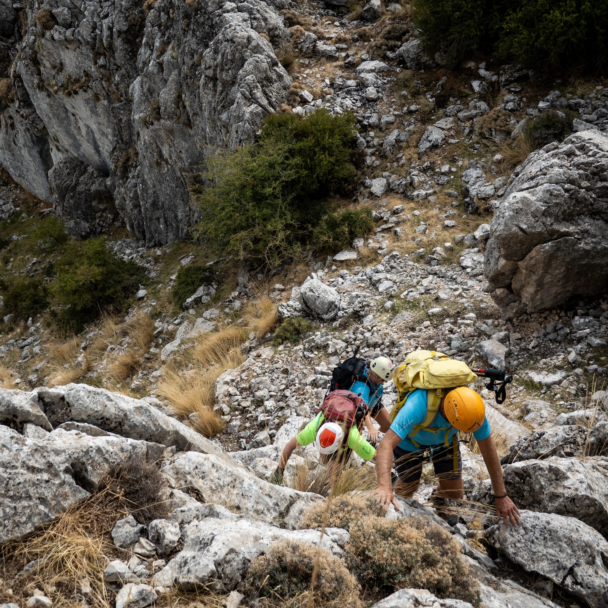Some helmeted climbers make their way up a ridge