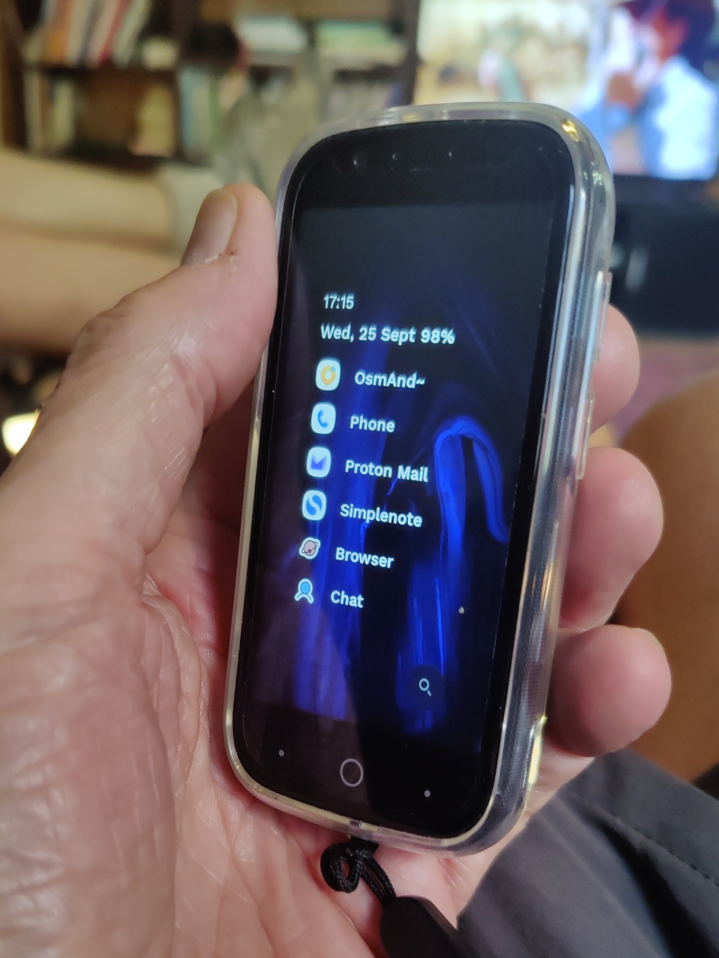 A small blue mobile phone is held in a person's hand