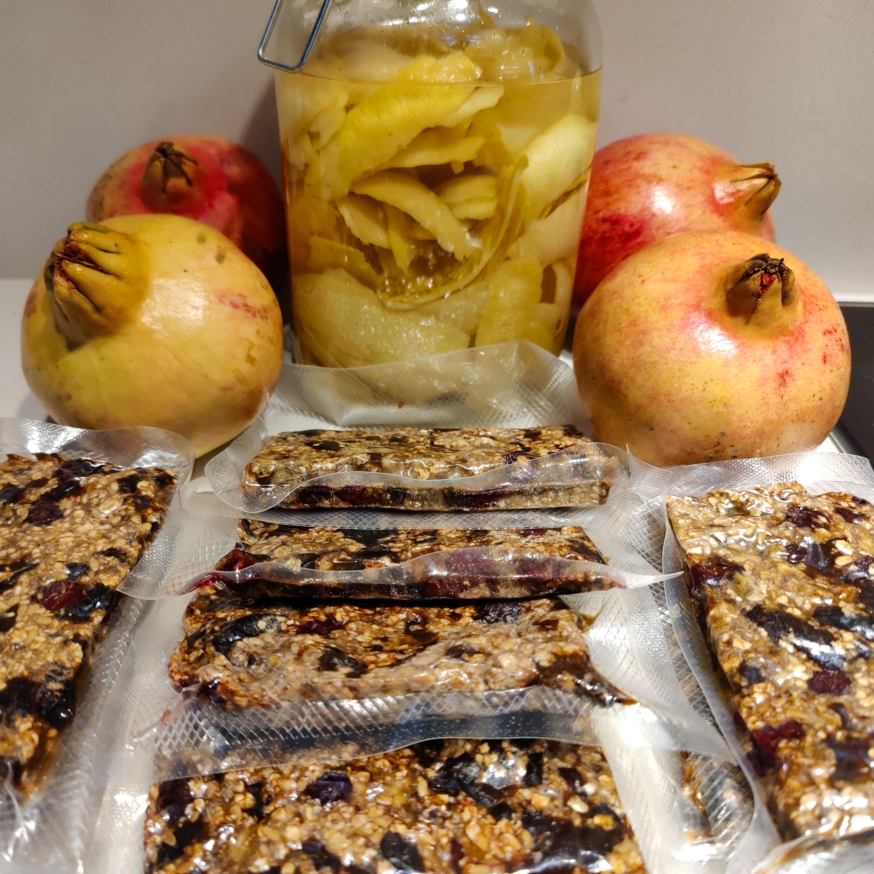 Lemon peel in a glass jar surrounded by pomegranites and granola bars