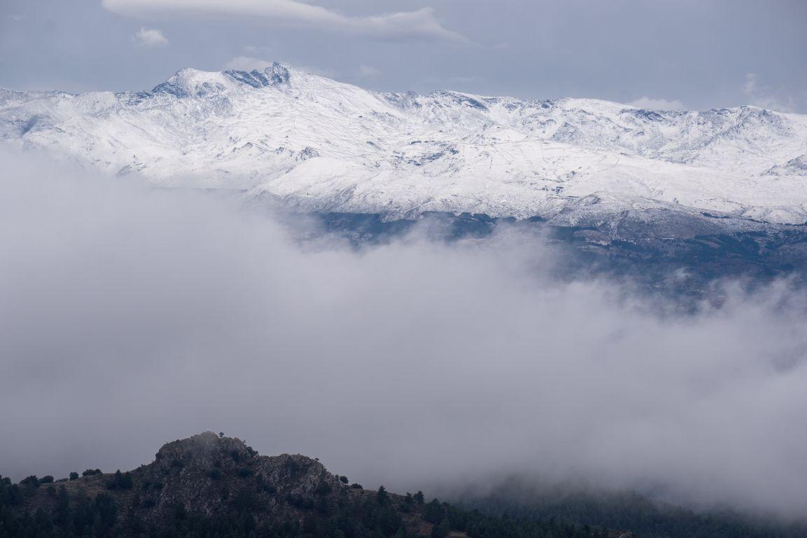 The snow covered Sierra Nevada from Veleta to Caballo is revealed above a layer of cloud