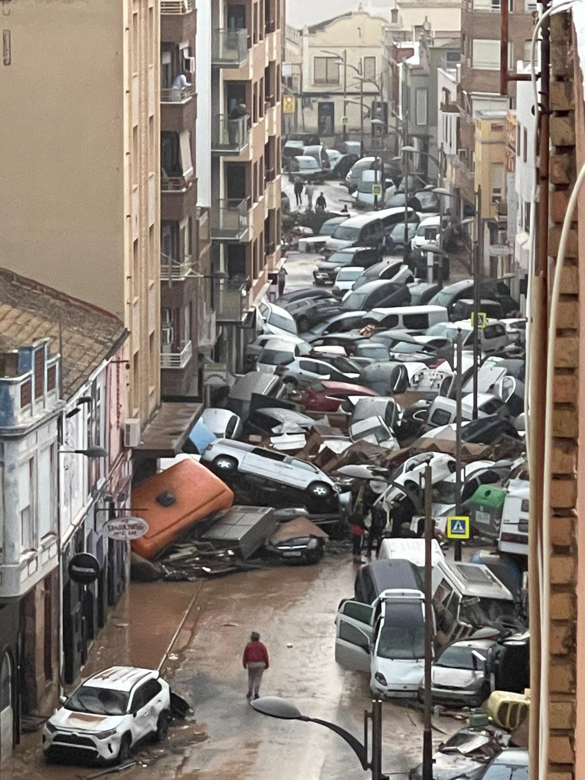 A street is filled with damaged and ruined vehicles after a severe flood.
