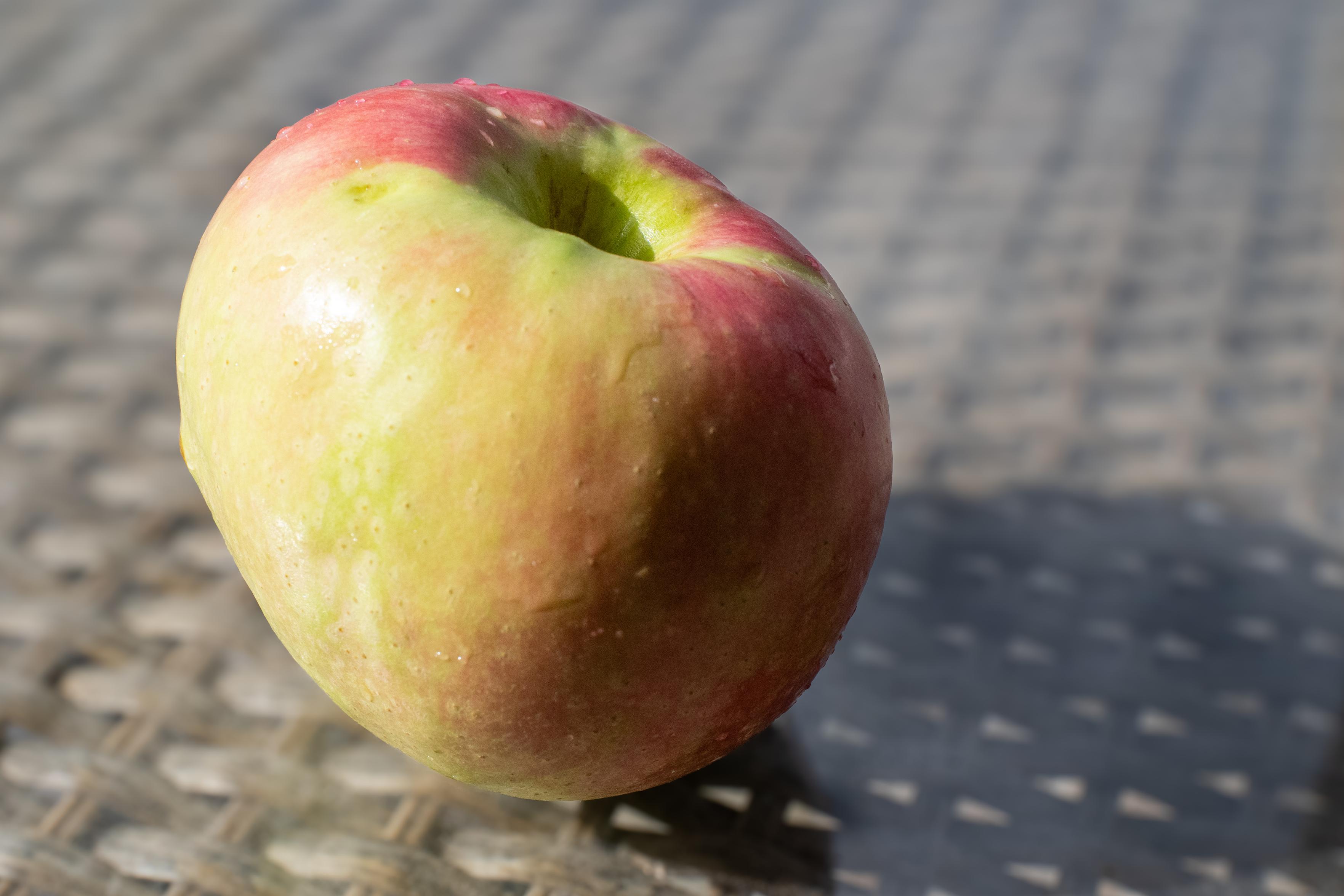 A pink lady apple sits on a table waiting to be eaten