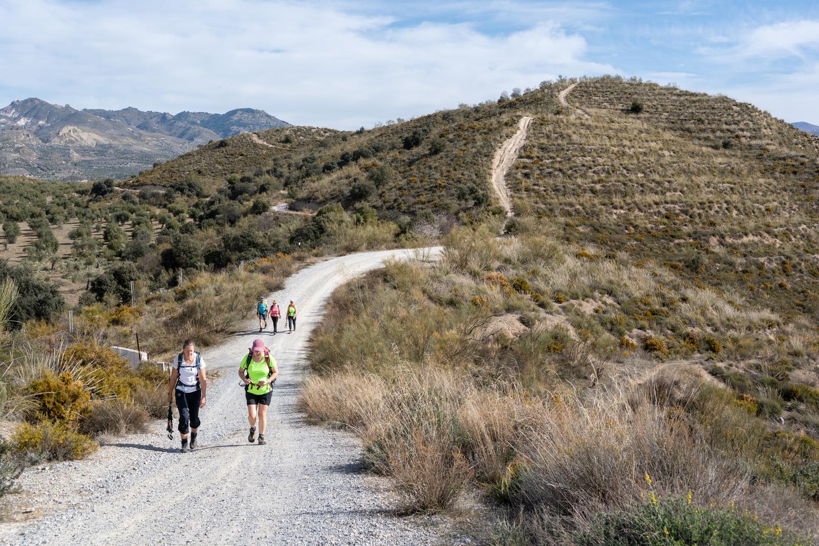 Hikers walking along a broad trail along a wide ridgeline