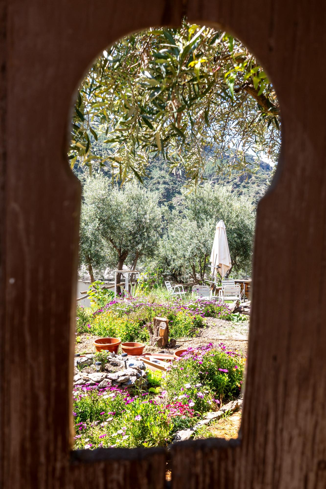 A keyhole window looks in on a beautiful and colorful garden