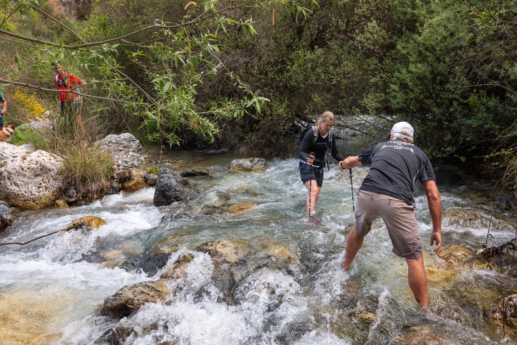Two hikers attempting to cross a fast flowing stream