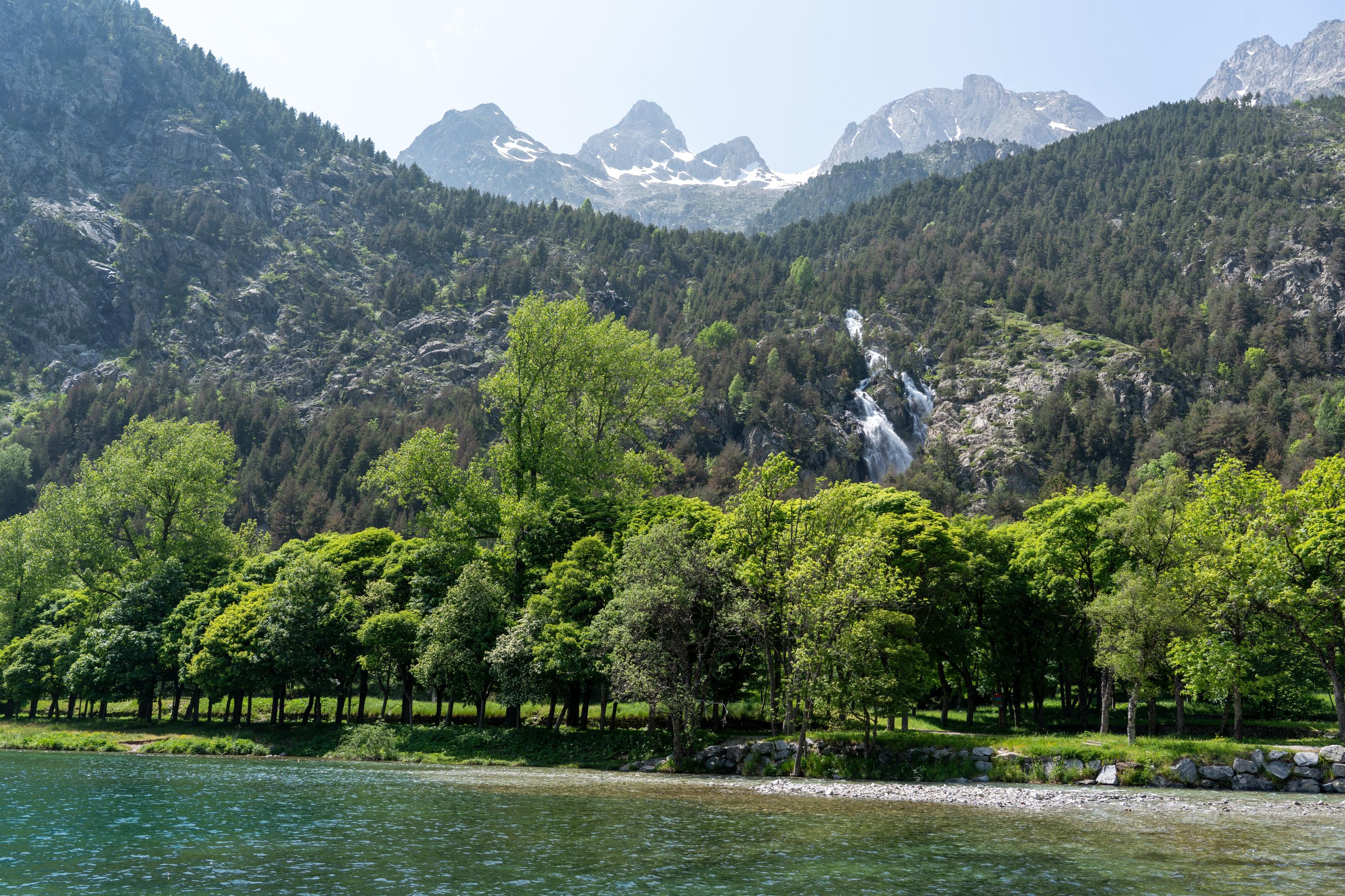 Looking across a lake to a waterfall, forest and snow mountains