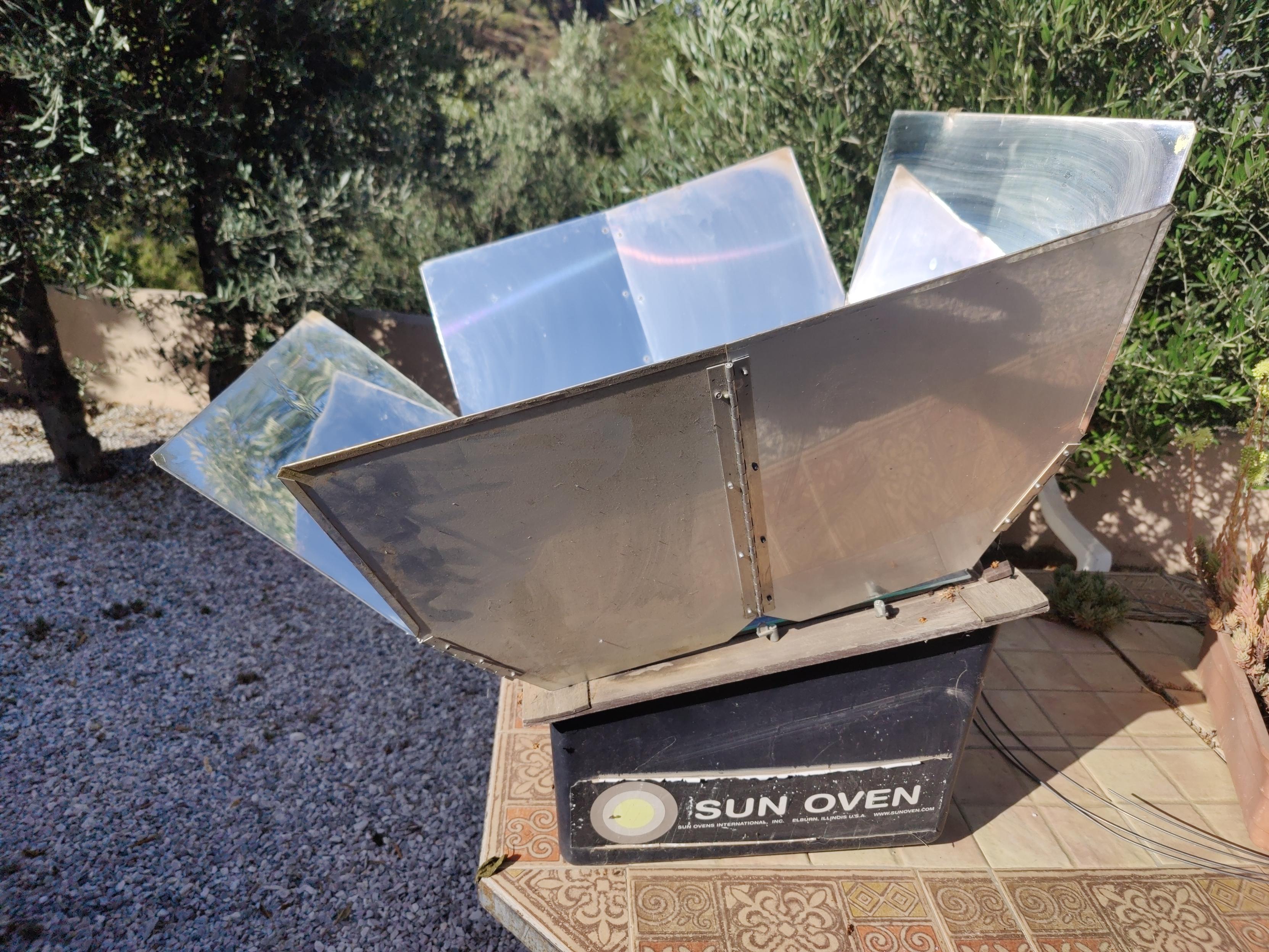 A sun oven with an aluminum parabolic shield directs the suns rays into a cooker