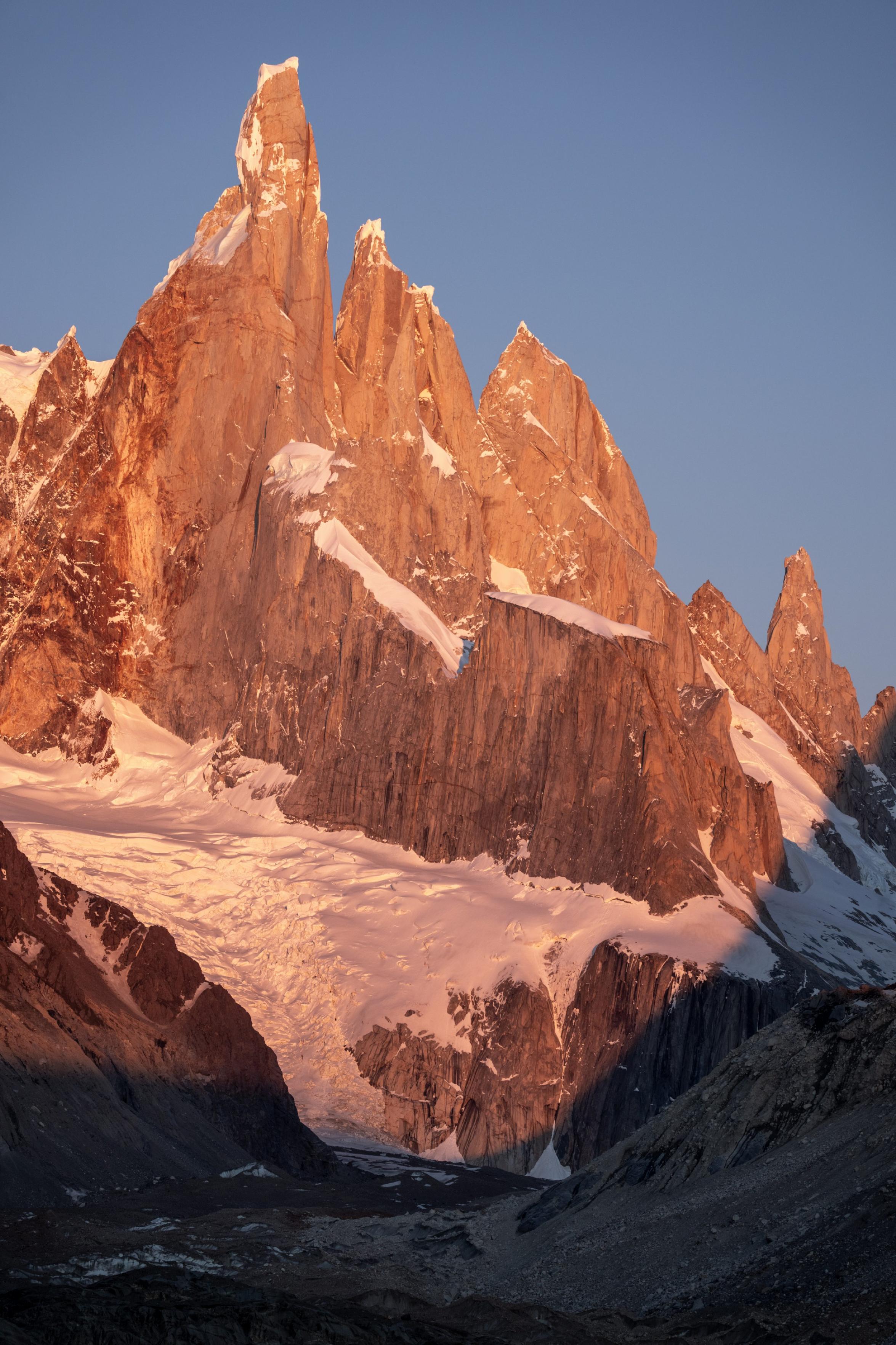 A orange mountain wall receives the first rays of the sun