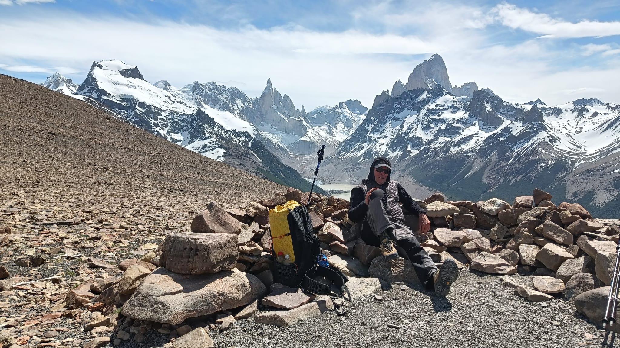 A wild and lonely bivouac place protected by rock walls lies in a scree strewn slope. The view to distant mountains of Cerro Torre and FitzRoy