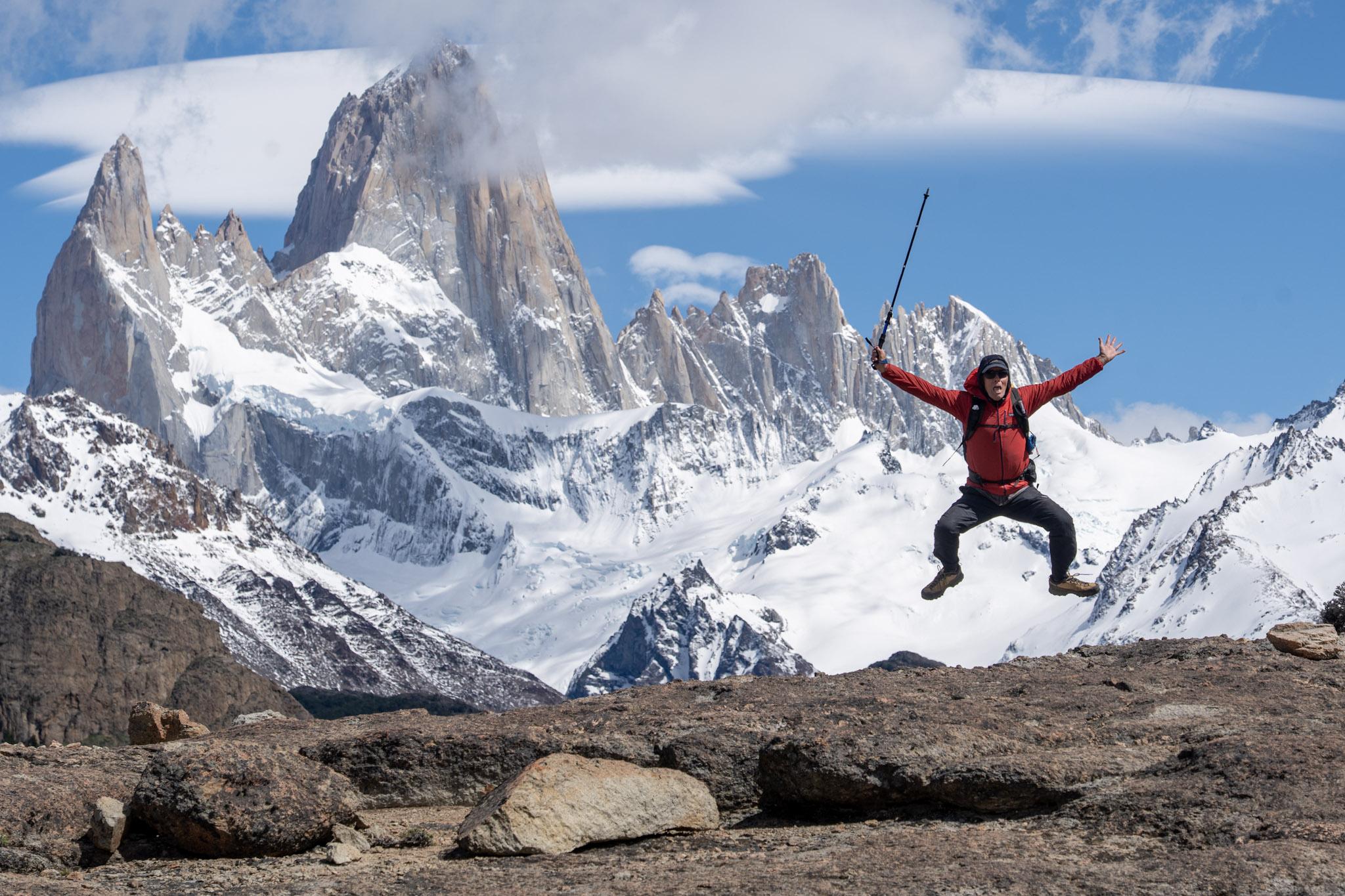 A person in red (me) has been persuaded by his partner to look ridiculous by jumping up in the air whilst she took a photo. Oh, the fabulous mountain in the background is Mt Fitzroy