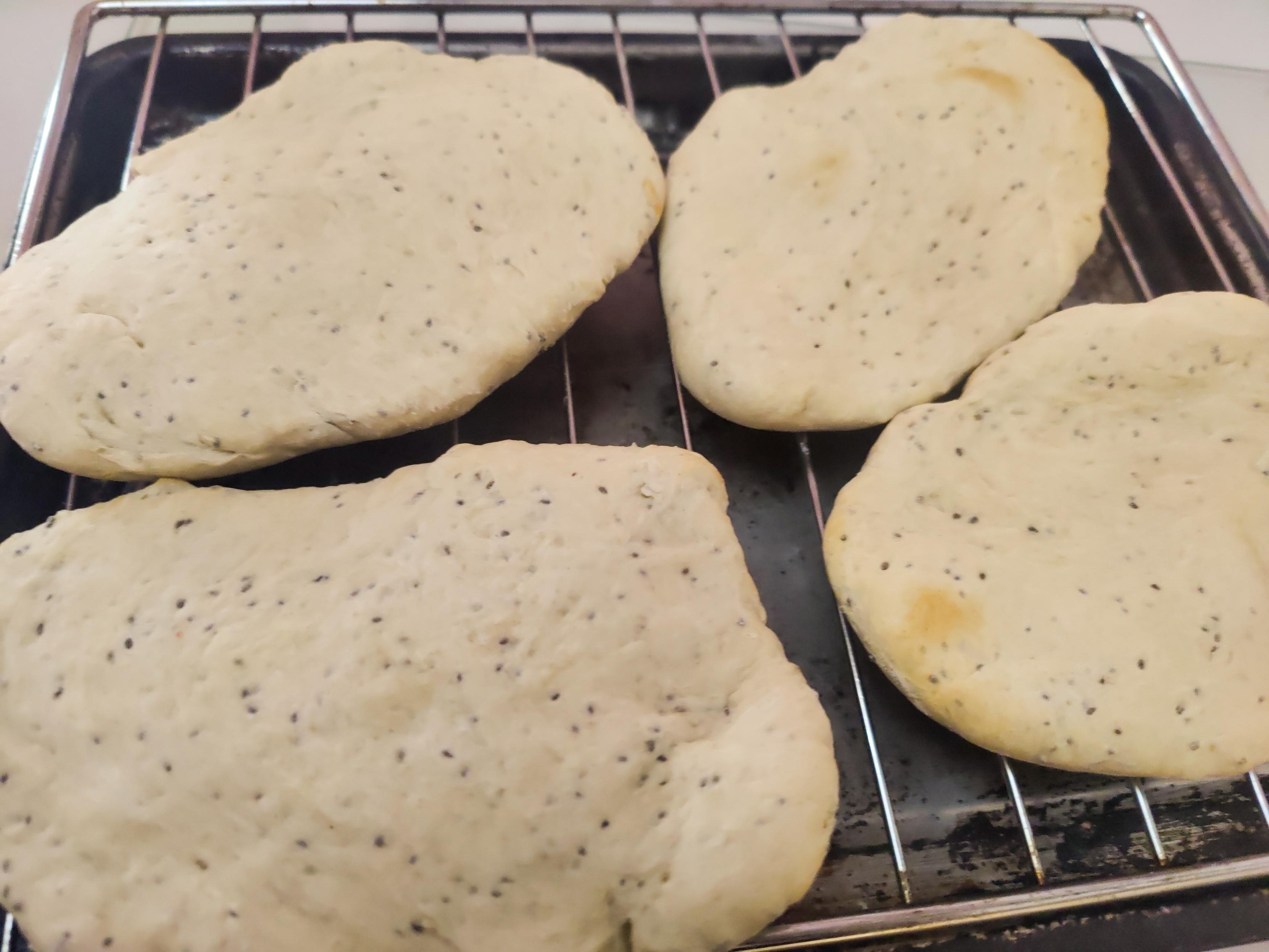4 pitta breads on a wire frame cooling after being brought out of the oven