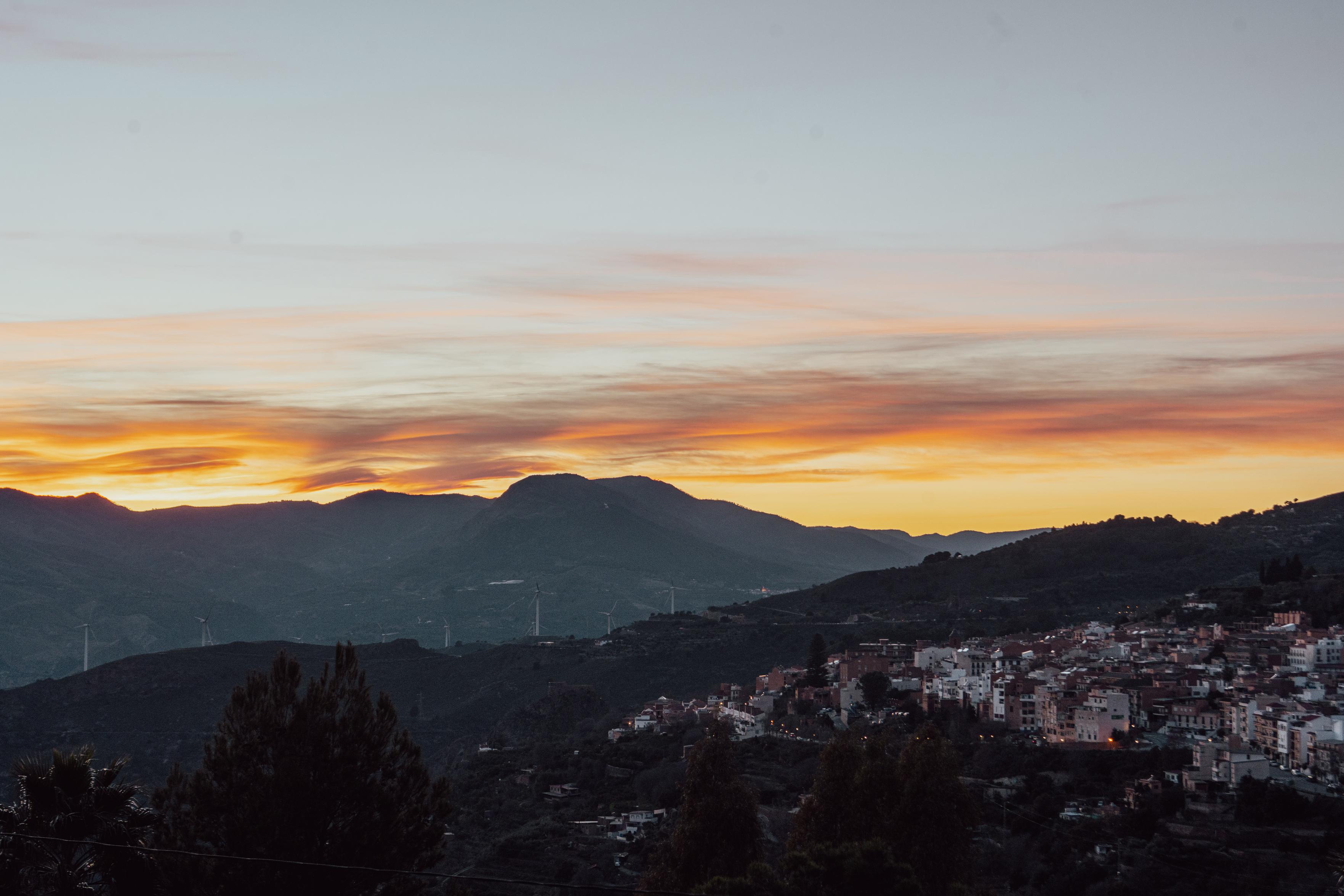 A sunset sky over some hills. The foreground has. Spanish town in the dusk