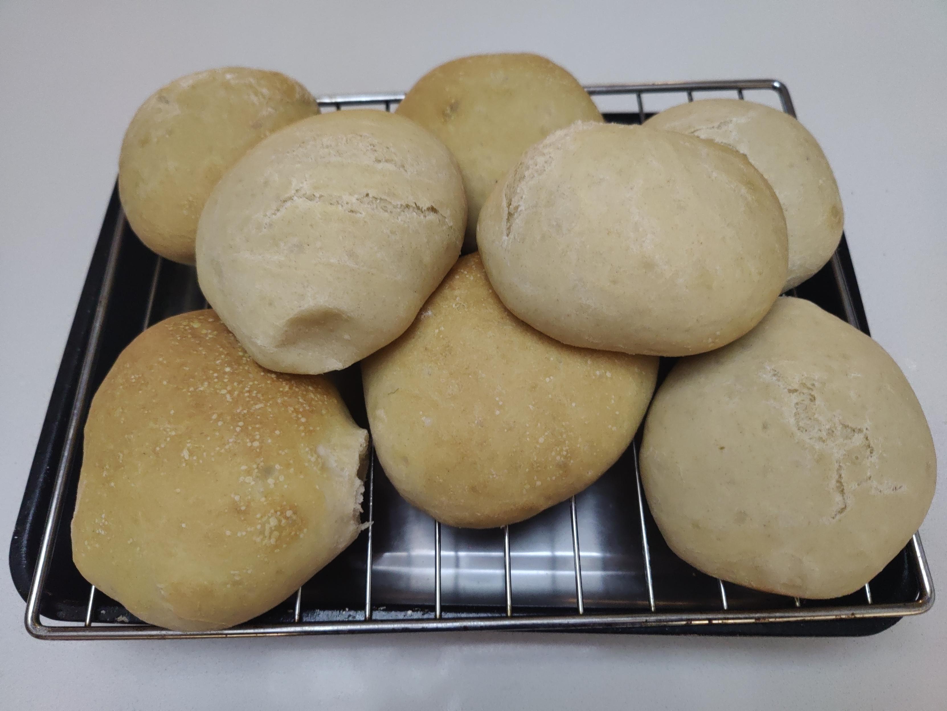 A mix of soft bread rolls sitting cooling on a wire frame