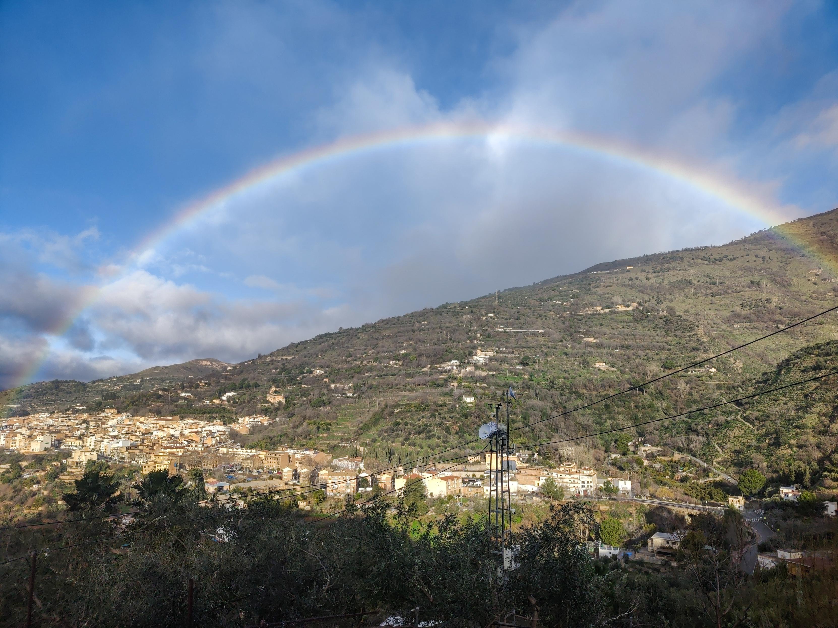 A rainbow over a Spanish town and hillside