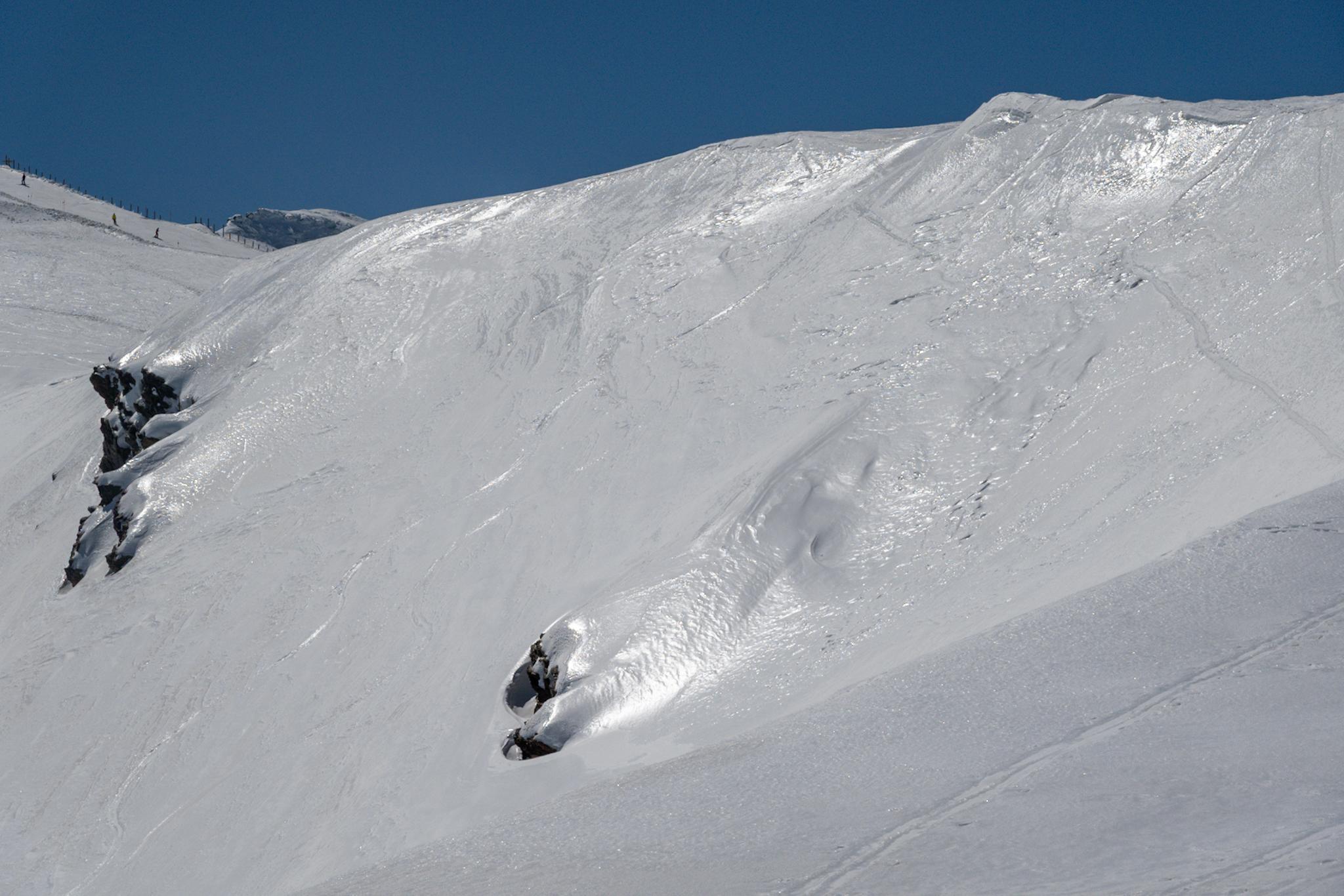 A mountainside covered in snow. Very few rocks showing through