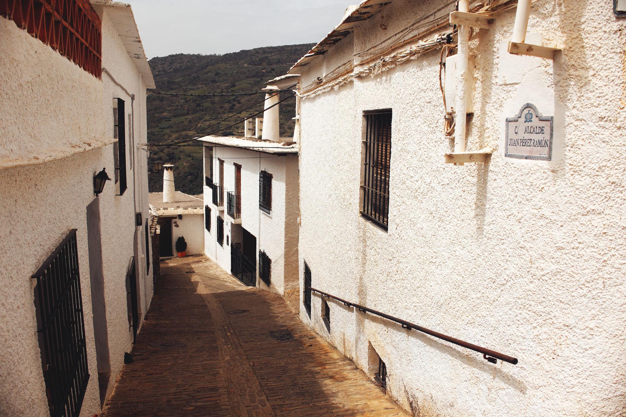 A narrow street, walls sunlit on the right hand side and in shadow on the left.